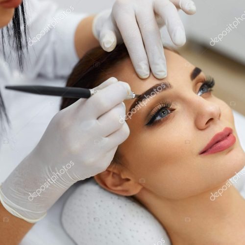 Permanent Makeup For Eyebrows. Closeup Of Beautiful Woman With Thick Brows In Beauty Salon. Beautician Doing Eyebrow Tattooing For Female Face. Beauty Procedure. High Resolution